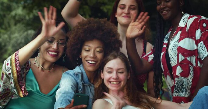  Portrait Shot of a Group of Female Friends in an Outdoor Park, Having a Video Call on Smartphone. Multiethnic Girls Smiling and Talking to their Friends, Keeping in Touch Thanks to Technology