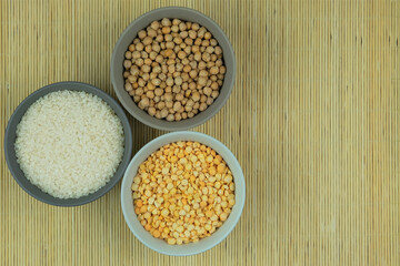 Rice, chickpeas and peas in plates on a straw background. Vegetarian organic product. Vintage view. Top view. Copy space.
