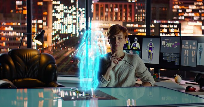 Female Fashion Designer Working with Holographic Augmented Reality 3D Model. Young Woman Creating New Clothing Collection. Scientific Technology. Night City Background.