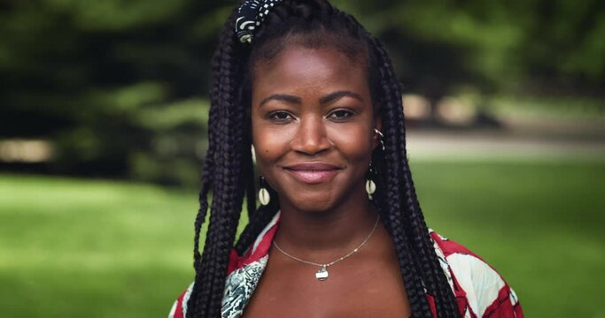 Black Young Woman Smiling, Waving the Rainbow LGBTQ+ Flag in a park in an Urban Area. Female Gen Z Activist Celebrating Love, Freedom, Equality and Diversity, Enjoying an Inclusive Community