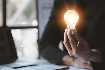 Man hold glowing light bulb, Creative new idea. Innovation, brainstorming, strategizing to make the...