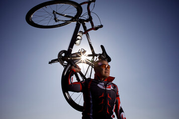 Male biker holds his bike up in the air and smiles.