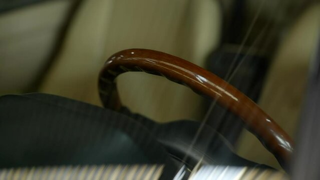 Stylish vintage wooden steering wheel behind car windshield reflecting under warehouse lighting
