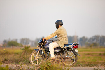 Indian rural man using helmet while drive on motorbike