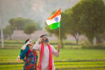 indian farmer couple saluting to national flag at agriculture field.
