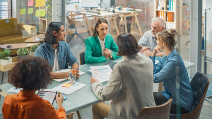 In the Stylish Modern Office Meeting Room: Diverse Group of Business Growth Marketing Professionals Use Laptop and Tablet, Discuss Project Ideas, Brainstorm Company Strategies. High Angle Shot.
