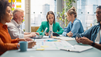 Office Meeting in Conference Room: Diverse Team of Professional Businesspeople Talking about Firm Strategy. Ambitious, Creative Start-up Team Using Laptop and Smartphones, Designing, Planning