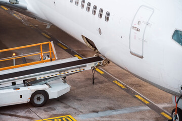 Open luggage compartment with tape equipment for unloading and loading luggage in a passenger plane.