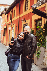 Fototapeta na wymiar Happy Tourists couple traveling at Rome, Italy, poses at the strets of Rome, Italy, taking a selfie with a smartphone