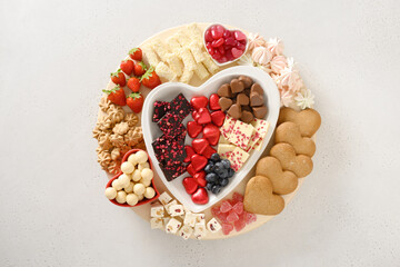 Charcuterie Valentines Day board with chocolate sweets, red hearts, cookies, marshmallow, strawberries, blueberries and candies isolated on white background. View from above.