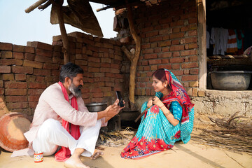 Indian farmer showing some detail to her wife in smartphone at home