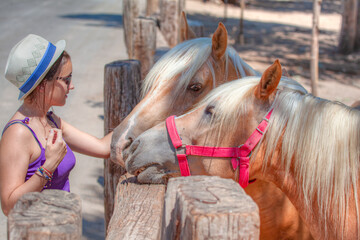 Beautiful auburn teenage girl stroking horse