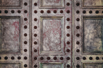 Detail of an ancient paneled door, with painted surface and decorative studs. Vintage background image with space for text