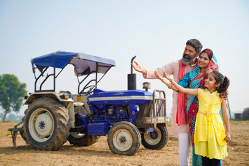 Rural indian farmer family Standing Together Near Tractor at field.