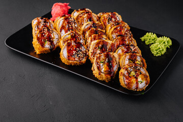 Served warm sushi with ginger and wasabi on a black stone plate