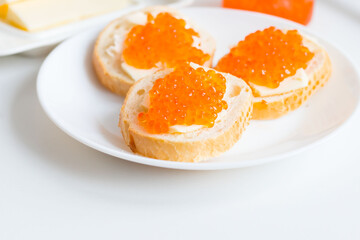 
Slices of bread with red caviar on a plate, on a white background.