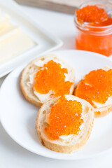 
Slices of bread with red caviar on a plate, on a white background.