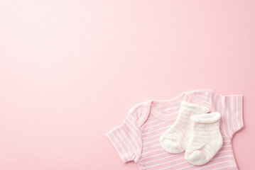 Infant clothes concept. Top view photo of pink shirt and tiny socks on isolated pastel pink background with copyspace
