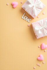 Valentine's Day concept. Top view vertical photo of pink present boxes with white ribbon bows heart shaped candles inscription love and sprinkles on isolated pastel beige background with blank space