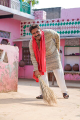 Indian farmer sweeping with a broom at home