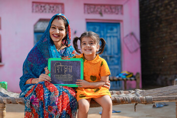education concept : Indian rural woman showing shiksha words in hindi calligraphy with daughter
