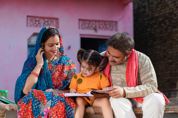 education concept : Indian parents teaching to little daughter at home.