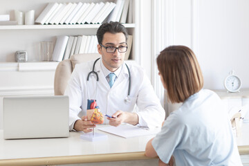 Fototapeta premium Young handsome male cardiologist talking to female patient about heart diseases 