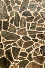 Fototapeta premium Wall of black cracked stones. Vertical image. Advertising space.