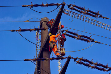 Two workers high up on power line pylon doing maintenance work on a sunny autumn day. Foto taken November 23rd, 2022, Zurich, Switzerland.