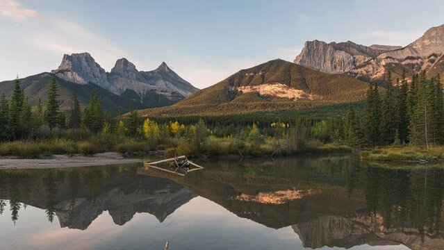 Sunrise over Three Sisters mountains in autumn forest reflection on pond at Canmore