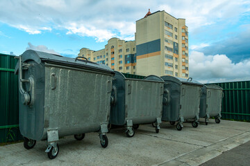 Modern metal containers for separate garbage collection. Garbage cans in the city on the background of a house. Environmental disaster, problems of waste removal, collection and disposal in a big city