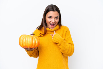 Fototapeta na wymiar Young caucasian woman holding a pumpkin isolated on white background with surprise facial expression