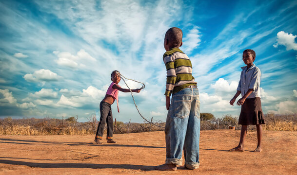 three african friends skipping rope in the village