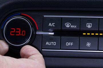 Set up air conditioner in the car. Hand turns air conditioner ring. Display indicates 23..0 degree...