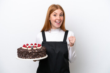 Young redhead woman holding birthday cake isolated on white background celebrating a victory in winner position