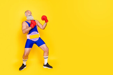 Fototapeta na wymiar Full size photo of sportive strong aged person boxing gloves punch empty space isolated on yellow color background