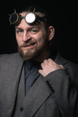 charismatic man in a classic suit and steampunk goggles on a black background stylish Portrait