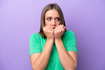 Young caucasian woman isolated on purple background nervous and scared putting hands to mouth