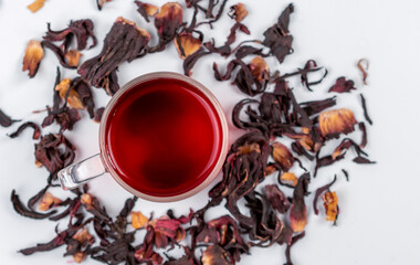 Healthy hibiscus tea and scattered hibiscus petals, top view. Hibiscus supports liver health, fights bacteria, fights inflammation and has more health benefits for a healthy lifestyle.