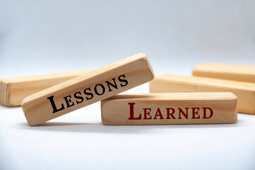 Lessons learned text on wooden blocks on white cover background. Lessons learned concept.