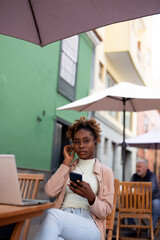 happy young woman using a mobile phone and earphones to make a call outdoor in the city