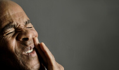 man with toothache having severe pain on grey background with people stock photo