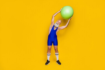 Full body photo of old trainer warmup before hard gym practicing hold green gymnastics ball advert equipment shop isolated on yellow color background