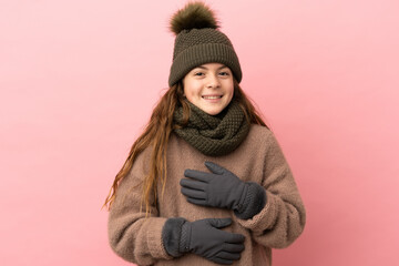 Little girl with winter hat isolated on pink background smiling a lot