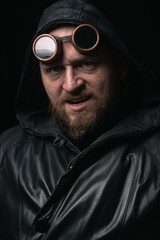 A man in a hood, wearing vintage steampunk goggles looking at the camera close-up