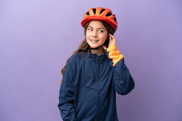 Little caucasian girl isolated on purple background listening to something by putting hand on the ear