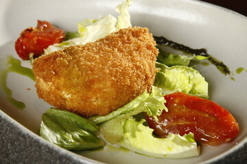 Deep fried breaded cheese with vegetables and tomatoes