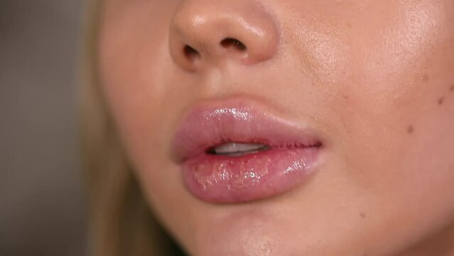 Closeup shot stylist applies lipstick to the lips of the female model. Woman making make up applying lipstick on a lip. Professional makeup. Tutorial makeup master class