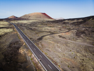 A cyclist rides along a road among volcanic craters, Lanzarote Island, Spain.