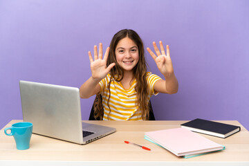 Little student girl in a workplace with a laptop isolated on purple background counting nine with fingers